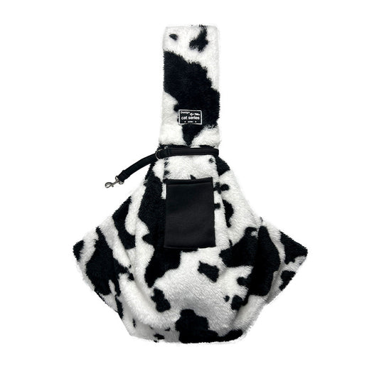 Front of the cow-print pet sling showing its shoulder strap and pocket
