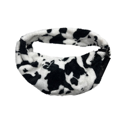 Side view of the cow-print pet sling showing the shoulder strap and pouch