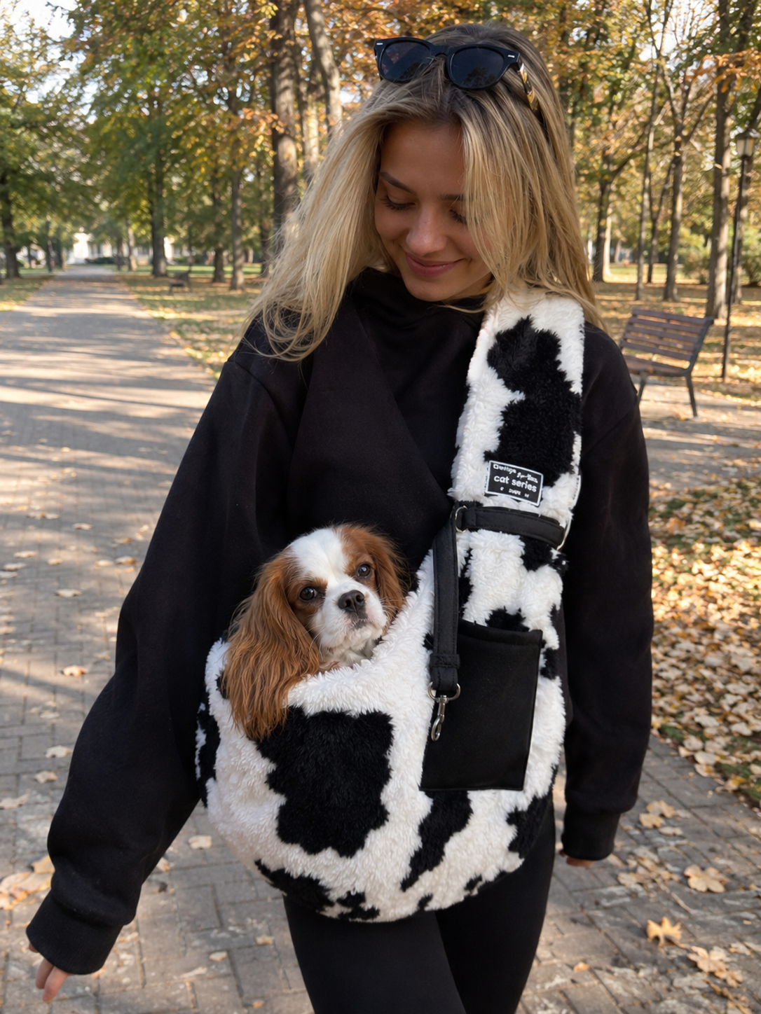 Small dog in the cow-print sling on an autumn walk